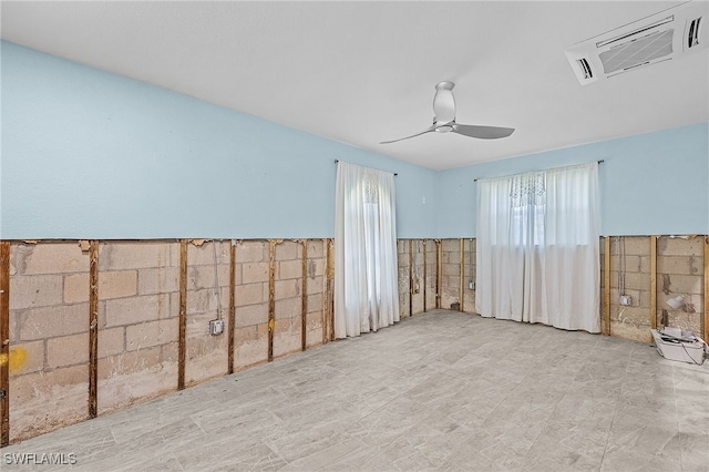 unfurnished room featuring a ceiling fan, a wainscoted wall, and visible vents