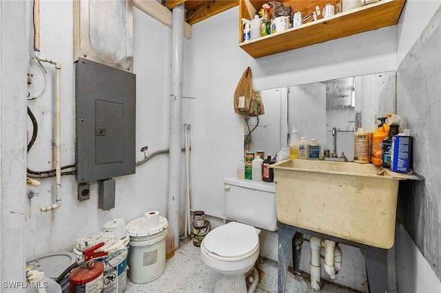 bathroom featuring toilet, electric panel, and a sink