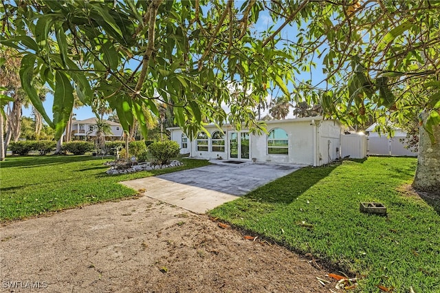 rear view of house with driveway, a yard, and fence