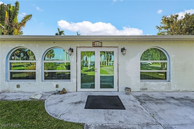 property entrance featuring french doors, a patio area, and stucco siding