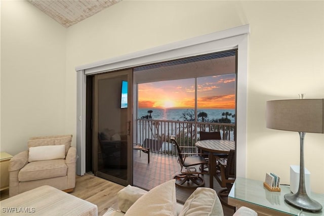 living room featuring vaulted ceiling, a water view, and wood finished floors