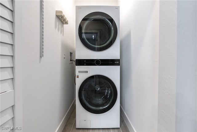 washroom featuring laundry area, stacked washing maching and dryer, and baseboards