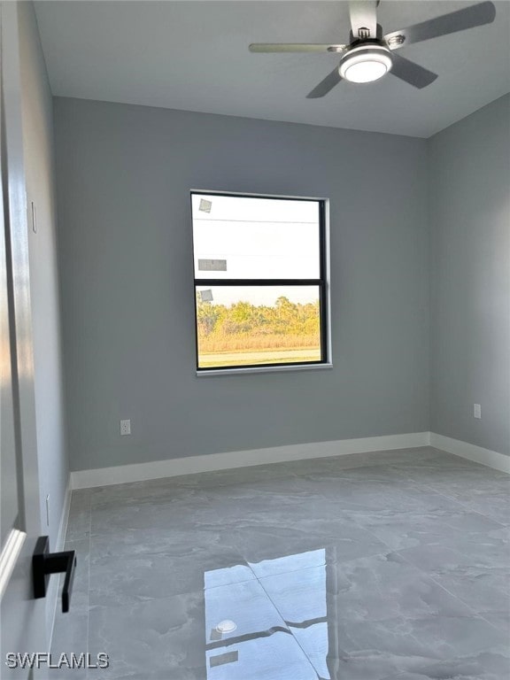 unfurnished room featuring a ceiling fan and baseboards