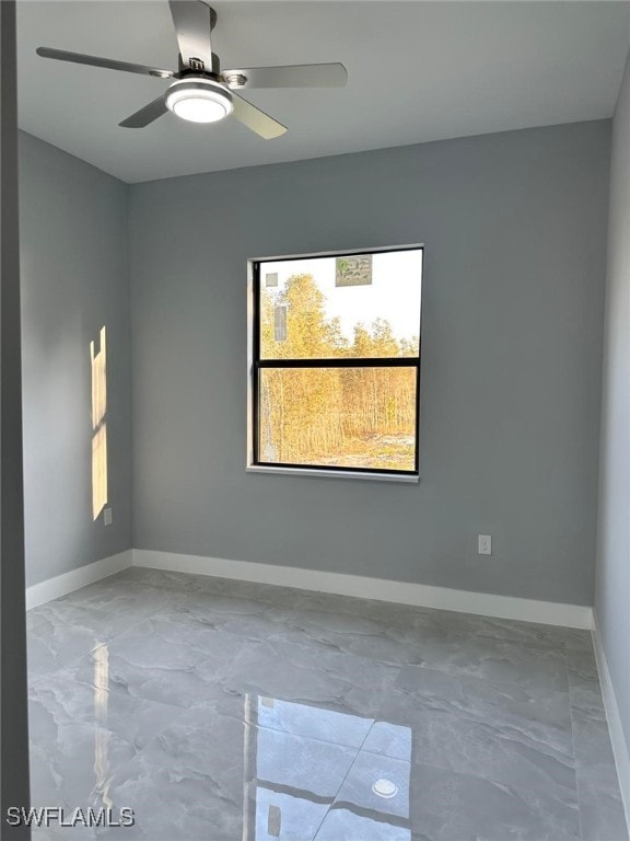 unfurnished room with a ceiling fan and baseboards