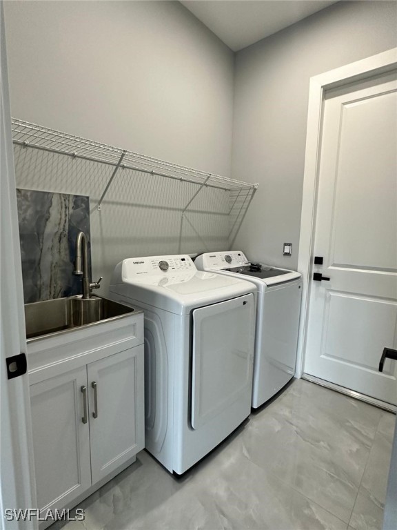 laundry room featuring cabinet space, a sink, and separate washer and dryer