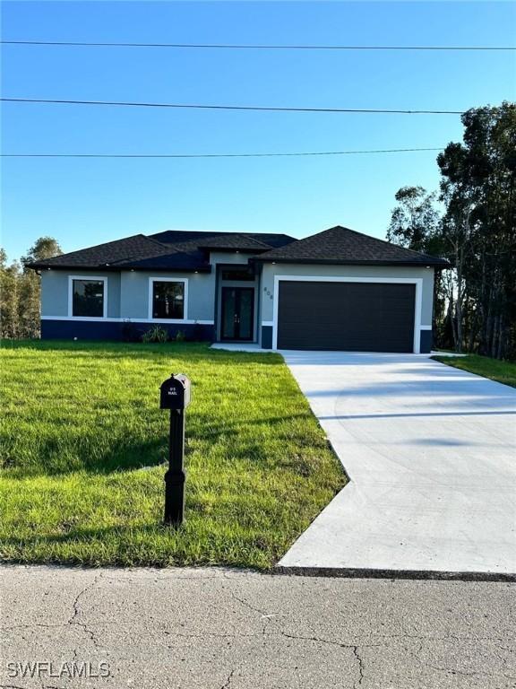 ranch-style home featuring a front yard, concrete driveway, a garage, and stucco siding