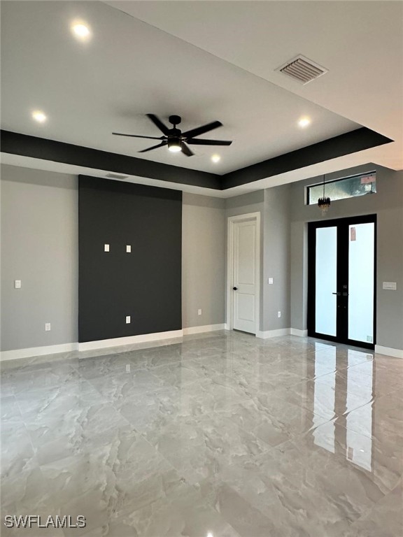 spare room featuring visible vents, baseboards, a tray ceiling, french doors, and marble finish floor