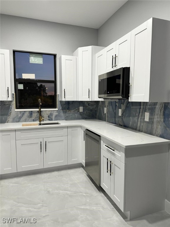 kitchen featuring stainless steel appliances, a sink, and white cabinets