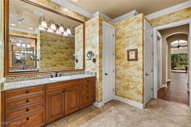 bathroom featuring wallpapered walls, baseboards, crown molding, and vanity