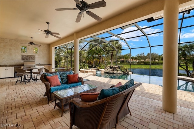 view of patio / terrace featuring a lanai, ceiling fan, a pool with connected hot tub, and exterior kitchen