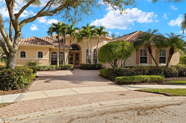 mediterranean / spanish-style home featuring a tiled roof, french doors, and stucco siding