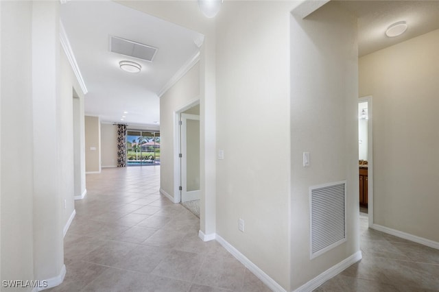 hall with crown molding, light tile patterned flooring, baseboards, and visible vents