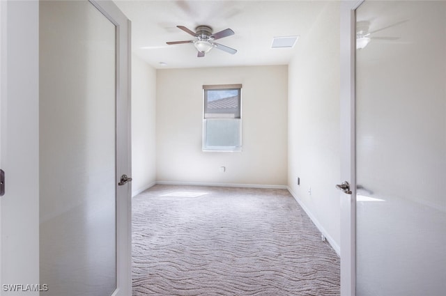 carpeted spare room featuring visible vents, baseboards, and ceiling fan