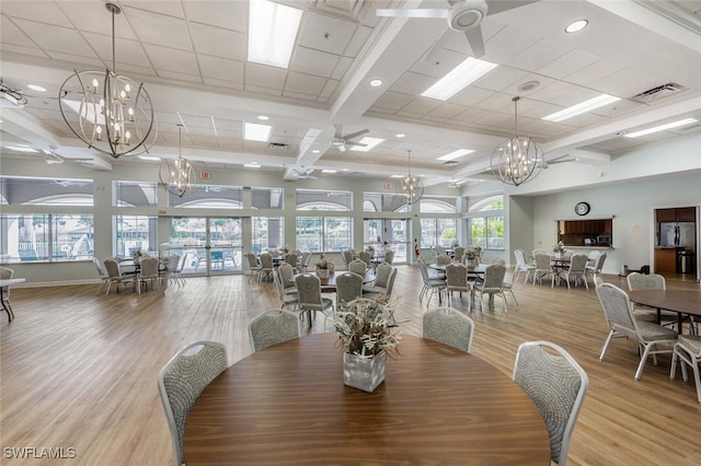 dining area with ceiling fan with notable chandelier, wood finished floors, and visible vents