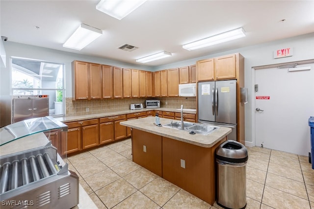 kitchen featuring white microwave, visible vents, light countertops, freestanding refrigerator, and light tile patterned flooring