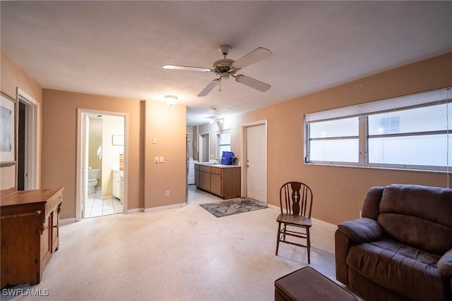 living area featuring light carpet, ceiling fan, and baseboards