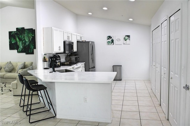 kitchen with stainless steel appliances, lofted ceiling, light tile patterned flooring, and a kitchen bar