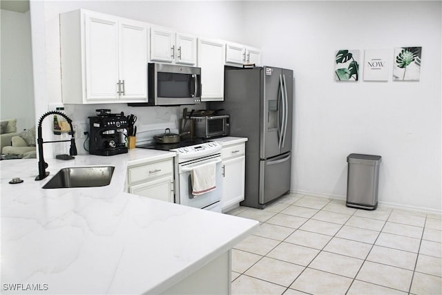 kitchen with light stone counters, appliances with stainless steel finishes, white cabinets, a sink, and light tile patterned flooring