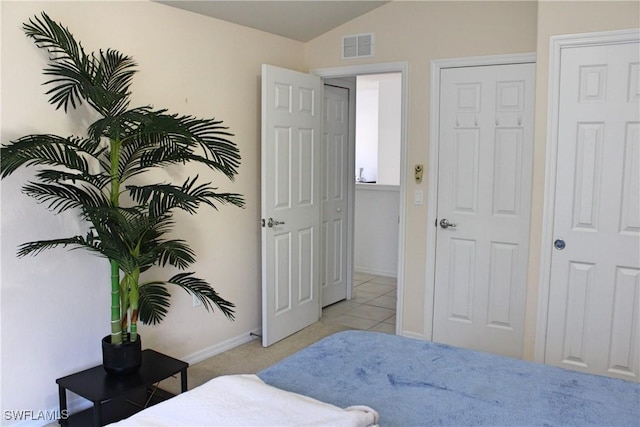 bedroom with lofted ceiling, visible vents, baseboards, and light tile patterned floors