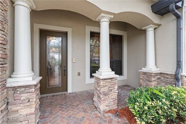 entrance to property with stone siding, covered porch, and stucco siding