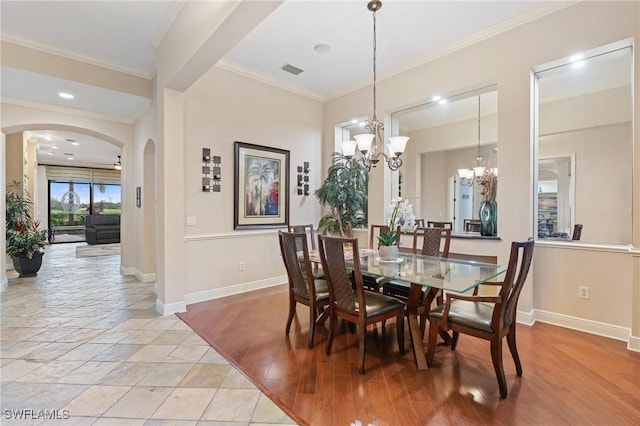 dining space featuring arched walkways, crown molding, visible vents, an inviting chandelier, and baseboards