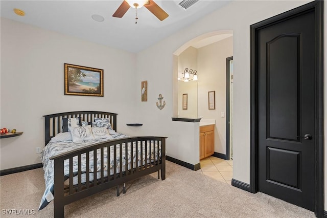 bedroom with baseboards, arched walkways, ensuite bathroom, and light colored carpet