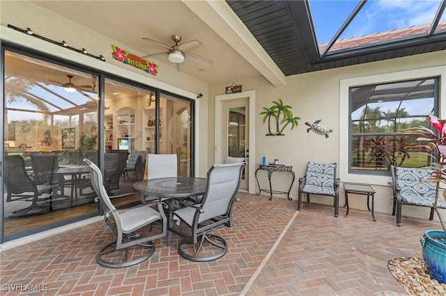 view of patio featuring glass enclosure, ceiling fan, and outdoor dining area