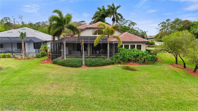 rear view of house with glass enclosure, a tile roof, and a lawn