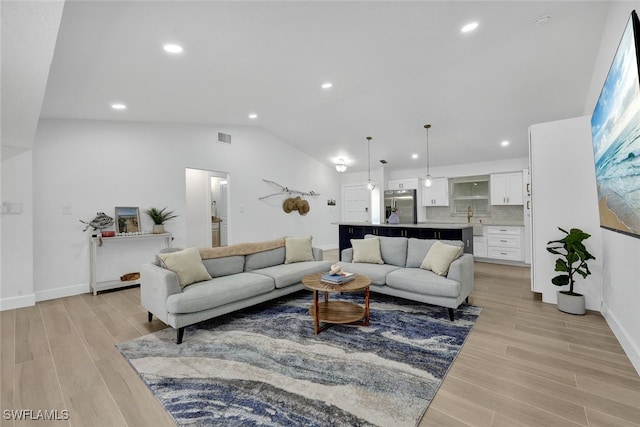 living room with visible vents, recessed lighting, baseboards, light wood-style floors, and lofted ceiling