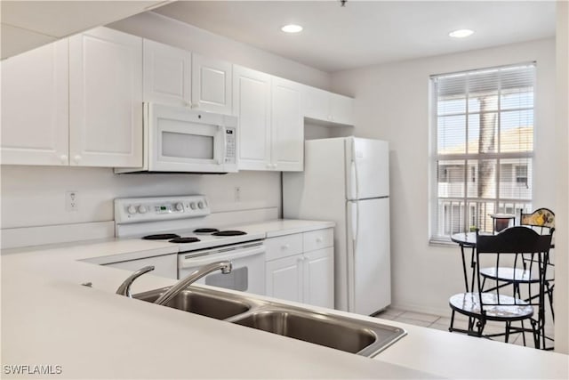 kitchen featuring light countertops, white appliances, white cabinets, and recessed lighting