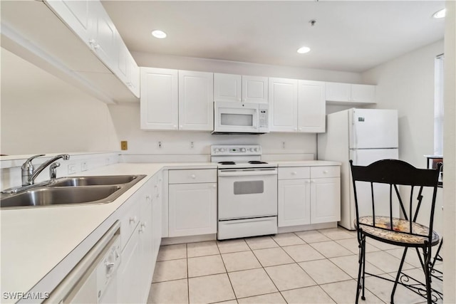 kitchen featuring white appliances, white cabinetry, a sink, and light tile patterned floors