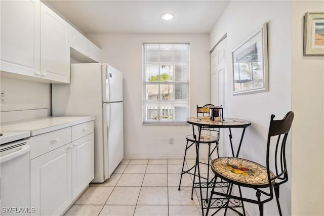 kitchen featuring light tile patterned floors, light countertops, white appliances, and white cabinetry