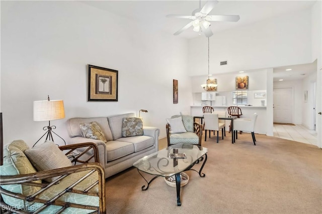 living room featuring visible vents, light carpet, ceiling fan, and a towering ceiling