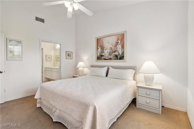 bedroom with baseboards, connected bathroom, visible vents, and light colored carpet