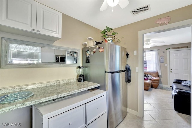 kitchen featuring visible vents, a ceiling fan, freestanding refrigerator, white cabinets, and light tile patterned flooring