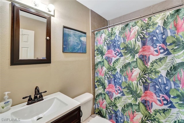 full bath with a textured wall, a shower with shower curtain, vanity, and toilet