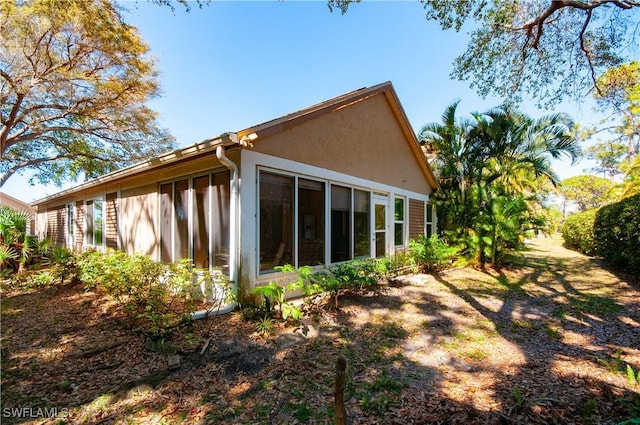 view of property exterior with a sunroom and stucco siding