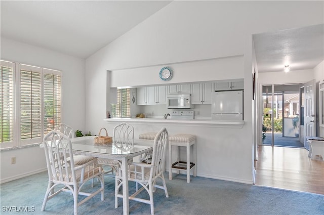 dining area with carpet flooring, vaulted ceiling, and baseboards