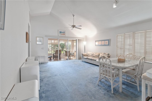 carpeted living area featuring high vaulted ceiling, rail lighting, decorative columns, and a ceiling fan