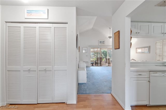 corridor with light wood finished floors, baseboards, visible vents, light colored carpet, and lofted ceiling