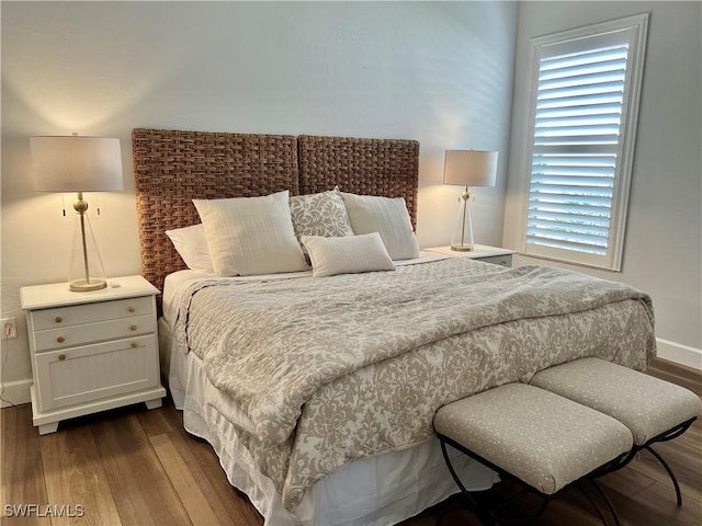 bedroom with baseboards and dark wood-type flooring