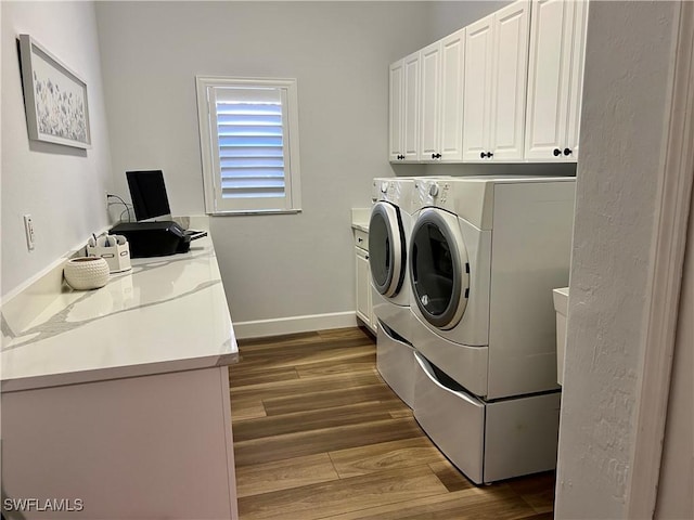 washroom with dark wood-type flooring, washing machine and dryer, cabinet space, and baseboards