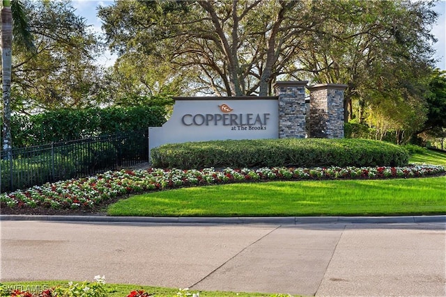 community / neighborhood sign with a yard and fence