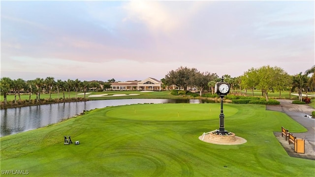 view of home's community with view of golf course, a yard, and a water view