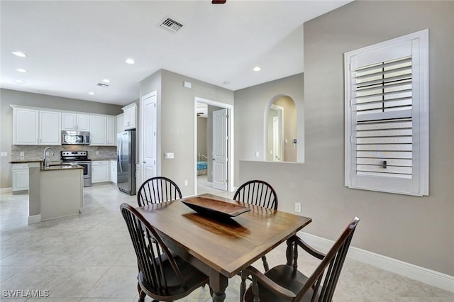 dining space with arched walkways, recessed lighting, visible vents, light tile patterned flooring, and baseboards