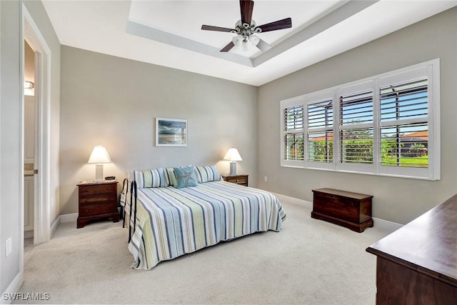 bedroom featuring ceiling fan, baseboards, a raised ceiling, and light colored carpet