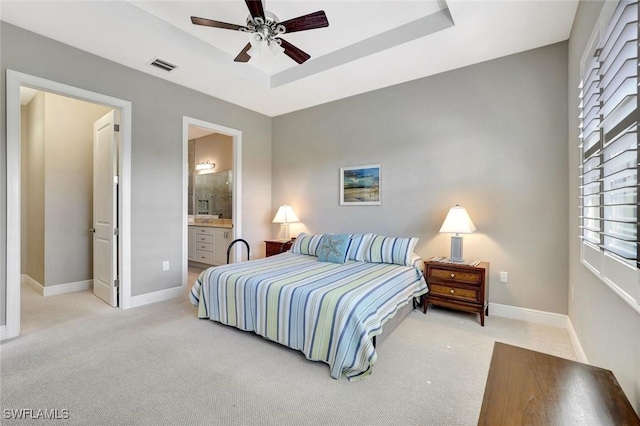 bedroom with baseboards, visible vents, a raised ceiling, and light colored carpet