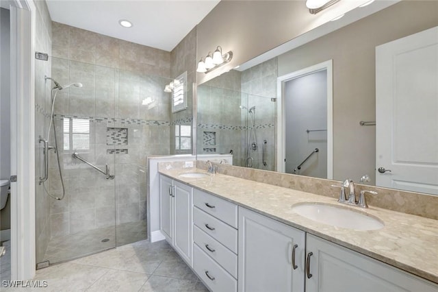 bathroom with toilet, a stall shower, double vanity, and a sink