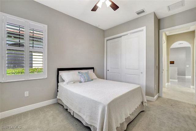 bedroom with light carpet, a closet, arched walkways, and visible vents