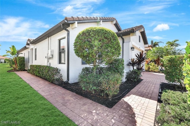 view of home's exterior featuring a garage, a lawn, and stucco siding